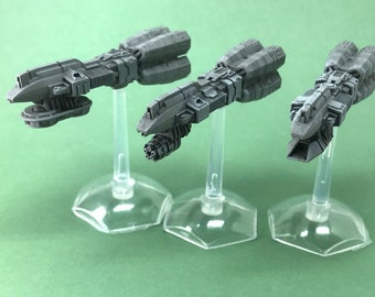 Pode incluir: Três naves espaciais cinzas, detalhadas e em miniatura em suportes de plástico transparente. As naves espaciais têm um design futurista com múltiplos motores e um nariz pontudo.