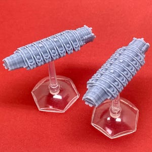 May include: Two gray 3D printed spaceship models on clear plastic bases. The spaceships are detailed with a series of ridges and lines.