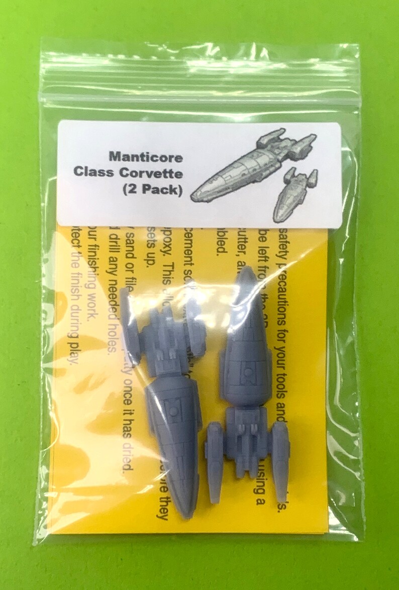 May include: Two gray plastic model spaceships, a larger one and a smaller one, in a clear plastic bag with a yellow label that reads "Manticore Class Corvette (2 Pack)".