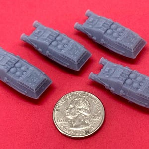 May include: Four gray plastic miniature spaceships with detailed designs. The spaceships are about the size of a US quarter.