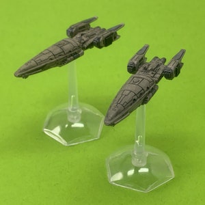 May include: Two miniature spaceships painted in a camouflage pattern, each on a clear plastic stand. The spaceships are detailed with a variety of panels and hatches.