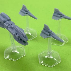 May include: Four miniature grey spaceships on clear plastic stands. The spaceships are different sizes and shapes, with one being much larger than the others.