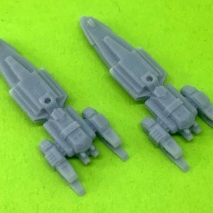 May include: Two gray plastic model spaceships with detailed designs and multiple engines. The spaceships are angled slightly to the right and left.