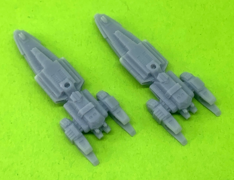 May include: Two gray plastic model spaceships with detailed designs and multiple engines. The spaceships are angled slightly to the right and left.