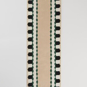 May include: A rectangular rug with a beige center and a geometric border. The border features black, white, and green shapes. The rug's design is symmetrical and modern, suitable for various interior styles.
