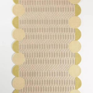 Pu&ograve; includere: Un tappeto rettangolare con un motivo beige strutturato. Il tappeto &egrave; bordato da cerchi beige e semicerchi verde tenue alternati. Il design del tappeto presenta linee verticali e orizzontali, creando un motivo geometrico.