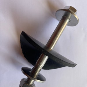 May include: A metal bolt assembly with a threaded end, a hexagonal nut, and a washer. A black rubber component is positioned between two washers. The bolt head is also hexagonal. The assembly is designed for fastening.