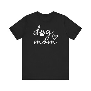 Könnte beinhalten: Schwarzes T-Shirt mit kurzen Ärmeln und weißem Text "dog mom" und einem Pfotenabdruck.