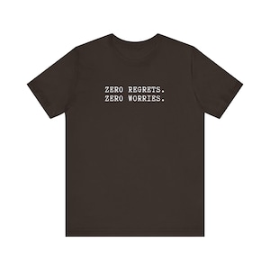 Könnte beinhalten: Ein dunkelbraunes T-Shirt mit dem Aufdruck "ZERO REGRETS. ZERO WORRIES." in weiß.