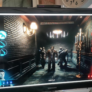 Może przedstawiać: Scena z gry wideo wyświetlana na monitorze Samsung. Gra przedstawia ciemny korytarz z ceglanymi ścianami i postaciami zombie. Widoczne są interfejsy gracza 1 i gracza 2, a także wskaźniki broni i zdrowia. Widoczny jest również tekst "FREE PLAY".