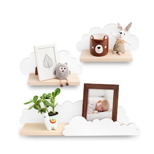 Peut inclure: Trois étagères en forme de nuage blanc avec des bases en bois. L'étagère du haut a une tasse en céramique brune avec un visage d'ours et un lapin blanc avec des accents bruns. L'étagère du milieu a une image encadrée en noir et blanc avec un motif de feuille et une figurine de hibou gris. L'étagère du bas a une plante succulente verte dans un pot en céramique blanc avec un motif de lama et une image encadrée d'un bébé endormi.