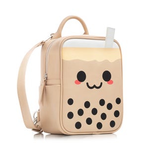 May include: A beige faux leather backpack shaped like a boba tea cup with a cute cartoon face and black boba pearls. The backpack has a zippered pocket on the front and a top handle.