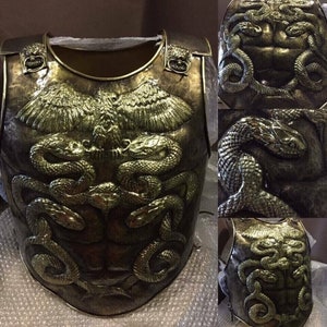 May include: A bronze-colored chest plate with a raised eagle design and two snakes intertwined on the front. The chest plate has a textured surface and is decorated with gold accents.