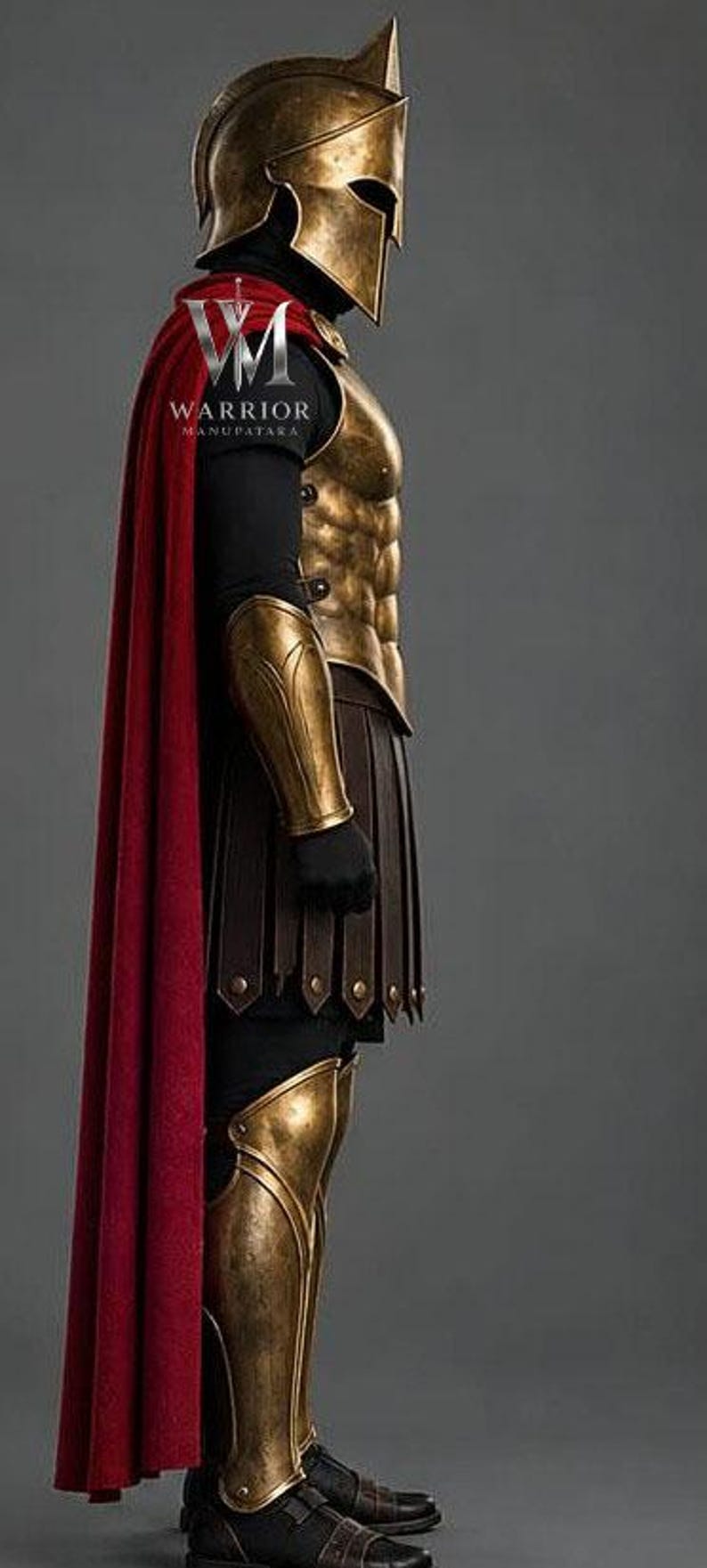 May include: A Spartan-style warrior costume featuring a metallic bronze Corinthian helmet, a matching breastplate with abdominal detailing, arm guards, and leg greaves. The ensemble includes a long red cape and a dark brown kilt-like skirt.