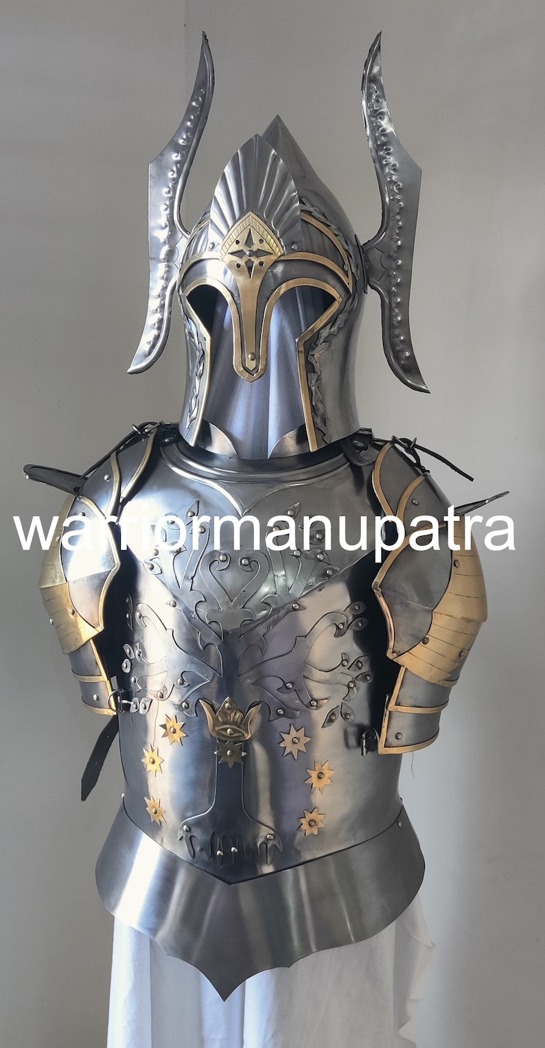 May include: A polished steel suit of armor featuring a helmet with two tall, curved side fins and a gold-trimmed visor. The chest plate displays an engraved tree motif accented with gold-toned star inlays and the text warformanupatra.