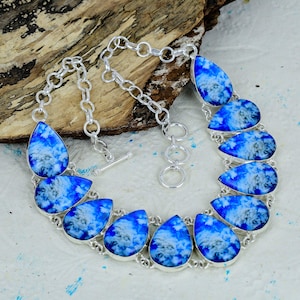 May include: A silver-toned necklace featuring a series of teardrop-shaped pendants with a vibrant blue and white cloud-like pattern. The pendants are linked together by silver-toned circular rings and include a toggle clasp closure mechanism.