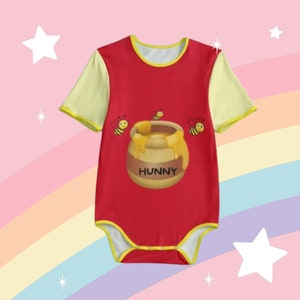 Puede incluir: Mono de bebé rojo y amarillo con un gráfico de un tarro de miel y abejas. El tarro de miel tiene la palabra "Hunny" escrita en él.