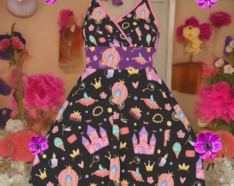 May include: A black sleeveless dress with a V-neckline and pink trim, featuring a repeating pattern of pink castles, carriages, crowns, combs, mirrors, and keys. The dress has a wide purple waistband and a flared skirt silhouette.