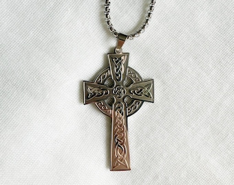 May include: A silver chain necklace with a silver Celtic cross pendant. The cross has intricate knotwork designs.