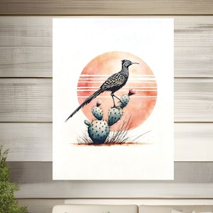Peut inclure: Une peinture à l'aquarelle d'un coureur des routes perché sur un cactus de figuier de Barbarie avec un coucher de soleil en arrière-plan.