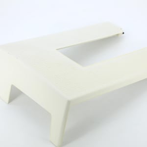 Peut inclure: Une table d'extension pour machine à coudre en plastique crème avec une découpe en forme de U. La surface supérieure présente une texture en grille fine, et l'unité est soutenue par deux pieds à l'avant, conçue pour offrir un espace de travail plat.