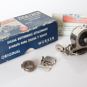 Könnte beinhalten: Ein Wurker Zickzack-Knopflochapparat für Nähmaschinen, bestehend aus einem blauen Karton mit weißer Schrift, einem Metallaufsatz mit schwarzem Einstellrad, zwei kleinen Metallplatten und einer Anleitung mit einer roten Abbildung.