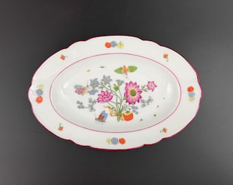 May include: White oval serving dish with a red rim and a floral design featuring pink, yellow, and blue flowers with butterflies.