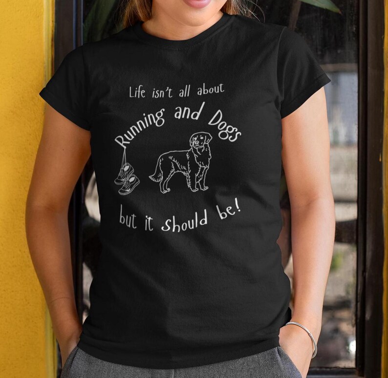 以下が含まれることがあります： 白のテキストとグラフィックが入った黒いTシャツ。「人生はランニングと犬だけではありませんが、そうあるべきです！」というテキスト。犬とランニングシューズの線画も特徴です。