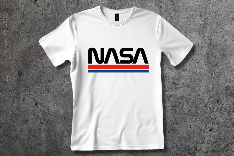 Może przedstawiać: Biała koszulka z czarnym logo NASA i czerwonymi i niebieskimi paskami.