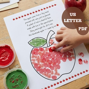 May include: A white paper sheet featuring a black outline of an apple with a green thumbprint leaf and red thumbprint fruit. The text reads: This apple came from a tiny hand, pressed with care, just as planned. A splash of red, a cheerful face, made with love in this special place. Shiny and bright for all to see, this handmade apple — made by me.