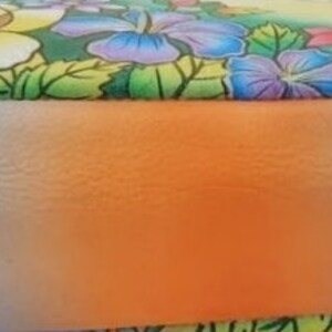 May include: A blue leather handbag with a floral print and a gradient ombre effect on the bottom. The bottom of the bag is a light blue color that fades to orange.