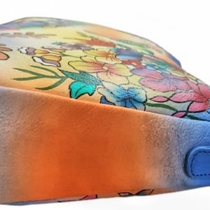 May include: A blue, orange, and yellow ombre handbag with a floral print. The bag has a single strap and a metal clasp.