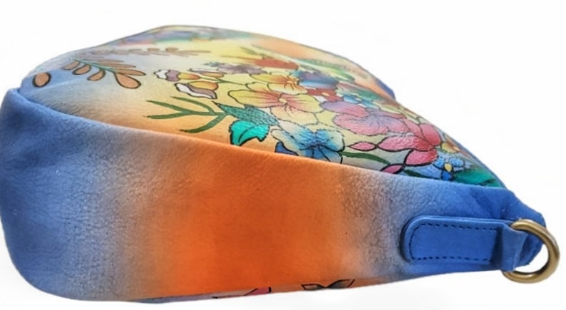 May include: A blue, orange, and yellow ombre handbag with a floral print. The bag has a single strap and a metal clasp.