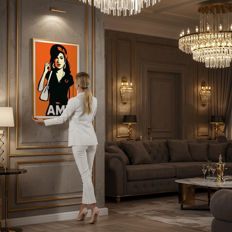 Pu&ograve; includere: Un ritratto in stile pop art arancione e nero di una donna con le iniziali "AM" in basso. L'opera &egrave; incorniciata ed esposta su una parete grigia. Una persona in un abito bianco tiene l'opera.