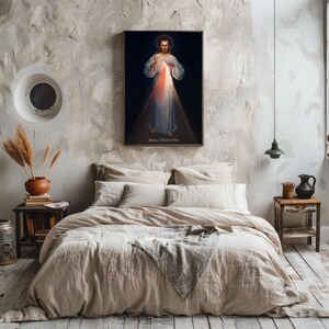 May include: A framed religious print depicting Jesus with light emanating from his chest, hanging above a bed with beige bedding. The text "Jesus, I trust in You" is visible at the bottom of the print.
