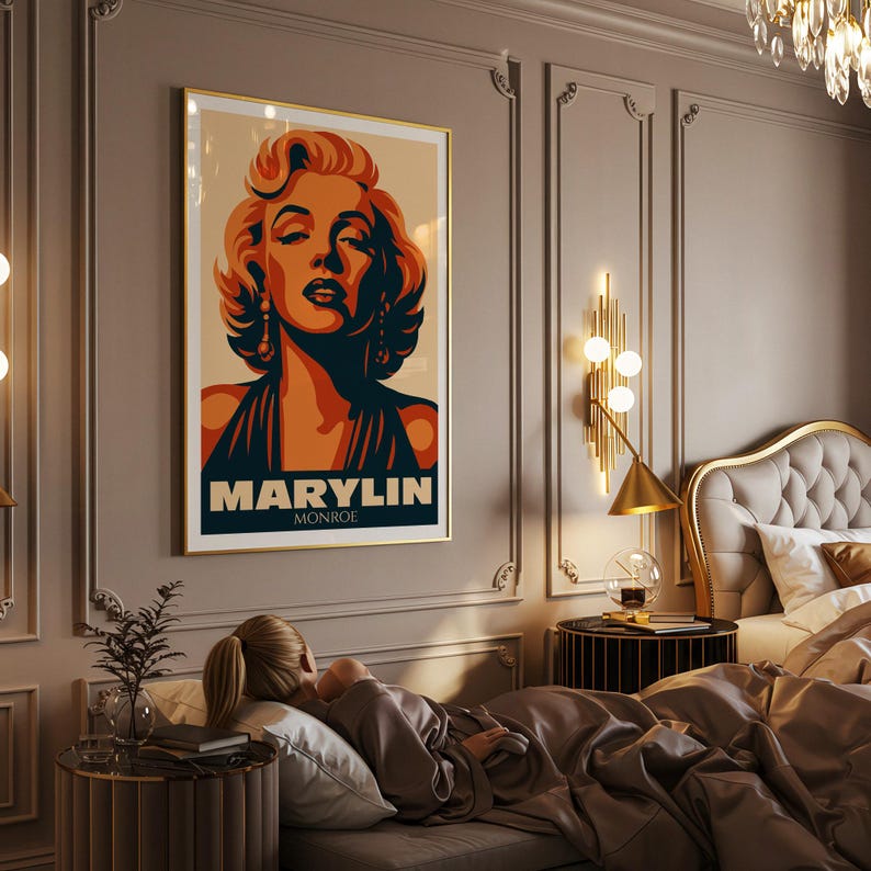 May include: A framed art print featuring a stylized portrait of Marilyn Monroe. The artwork uses a palette of orange, black, and beige. The text "MARYLIN MONROE" is displayed at the bottom of the print.