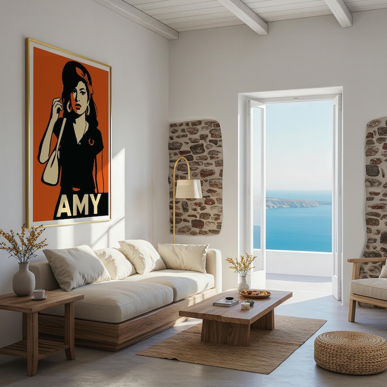 Pu&ograve; includere: Un soggiorno con un grande poster pop art incorniciato di una donna con il nome "AMY" in lettere bianche. La stanza presenta un divano colorato chiaro, un tavolino di legno e una vista sull'oceano attraverso una porta aperta.