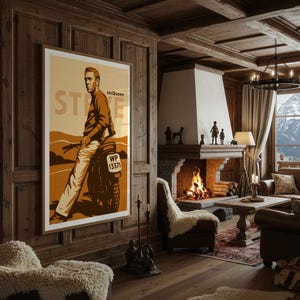 May include: A framed poster featuring Steve McQueen leaning on a motorcycle. The poster has a tan and brown color scheme with the name "McQueen" and the word "STEVE" printed on it. The motorcycle has the license plate "WP 13371".
