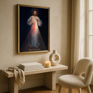 May include: A framed religious artwork depicts a figure in white robes with a halo, radiating light. The text "Jesus, I trust in You" is at the bottom. The artwork hangs above a stone bench with a candle, vase, and a stack of boxes.
