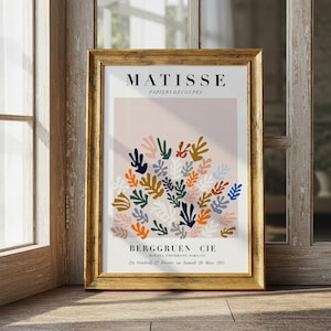 Peut inclure: Une affiche encadrée avec un cadre doré, présentant un design abstrait coloré de Matisse. L'affiche a un fond rose clair avec un groupe de formes en forme de feuilles de différentes couleurs. Le texte "MATISSE PAPIERS DÉCOUPÉS" et "BERGGRUEN CIE" est inclus.