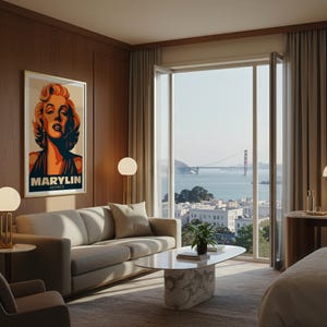 May include: A living room with a framed poster of Marilyn Monroe, a light-colored sofa, and a marble coffee table. The room has a large window with a view of the Golden Gate Bridge and the San Francisco skyline.