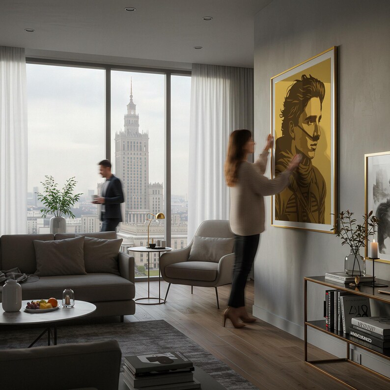 May include: A framed portrait with a gold border hangs on a gray wall. The artwork features a stylized image of a person in shades of brown and yellow. The room has a modern design with a sofa, chair, and a view of a city.
