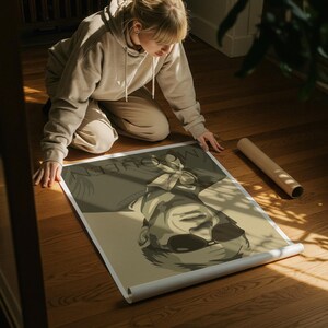 May include: A rolled poster featuring a sepia-toned illustration of a person wearing sunglasses. The poster has the word "MCQUEEN" printed at the top. The poster is on a wooden floor.