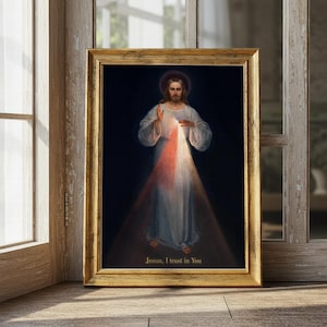 Puede incluir: Una impresión religiosa enmarcada que presenta una figura con túnicas blancas con una luz roja y blanca que emana del pecho. La imagen tiene un fondo oscuro y el texto "Jesus, I trust in You". El marco es dorado.