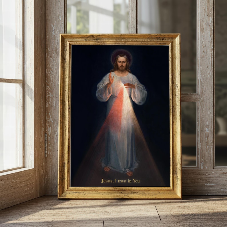 May include: A framed religious print featuring a figure in white robes with a red and white light emanating from the chest. The image has a dark background and the text "Jesus, I trust in You" at the bottom. The frame is gold.