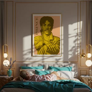 Op de afbeelding: Een ingelijste poster met een gestileerd portret van Prince in geel en bruin. Het woord "PRINCE" staat verticaal afgedrukt. De poster hangt boven een bed met turquoise en witte kussens en een turquoise deken. De kamer heeft gouden accenten.