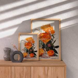 May include: Two framed prints of a glass of orange juice with orange slices and flowers. The larger print says "Sparkle" and the smaller print says "Lemonade".