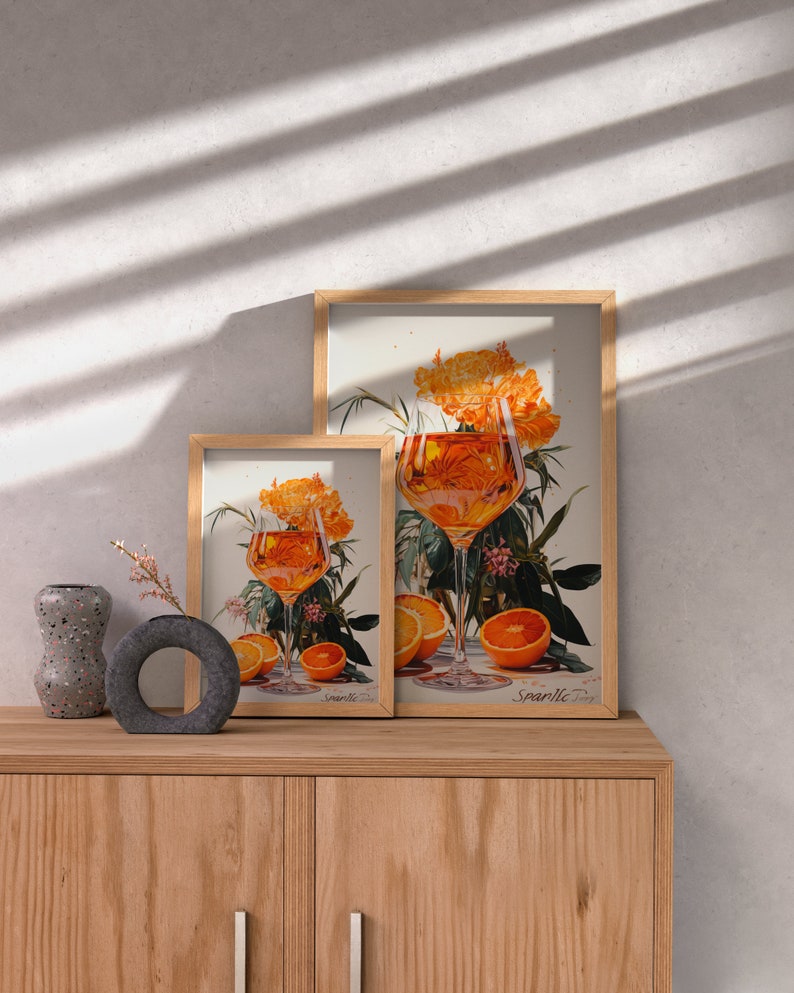 May include: Two framed prints of a glass of orange juice with orange slices and flowers. The larger print says "Sparkle" and the smaller print says "Lemonade".