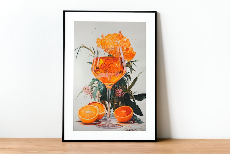 May include: A framed illustration of a glass of orange juice with orange slices and orange blossoms. The illustration is in a black frame and has the artist's signature "Svanile" in the bottom right corner.