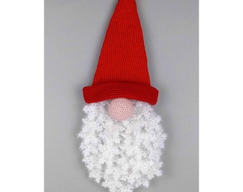 May include: A red crocheted gnome with a white crocheted beard and a pink nose. The gnome is hanging from a string.